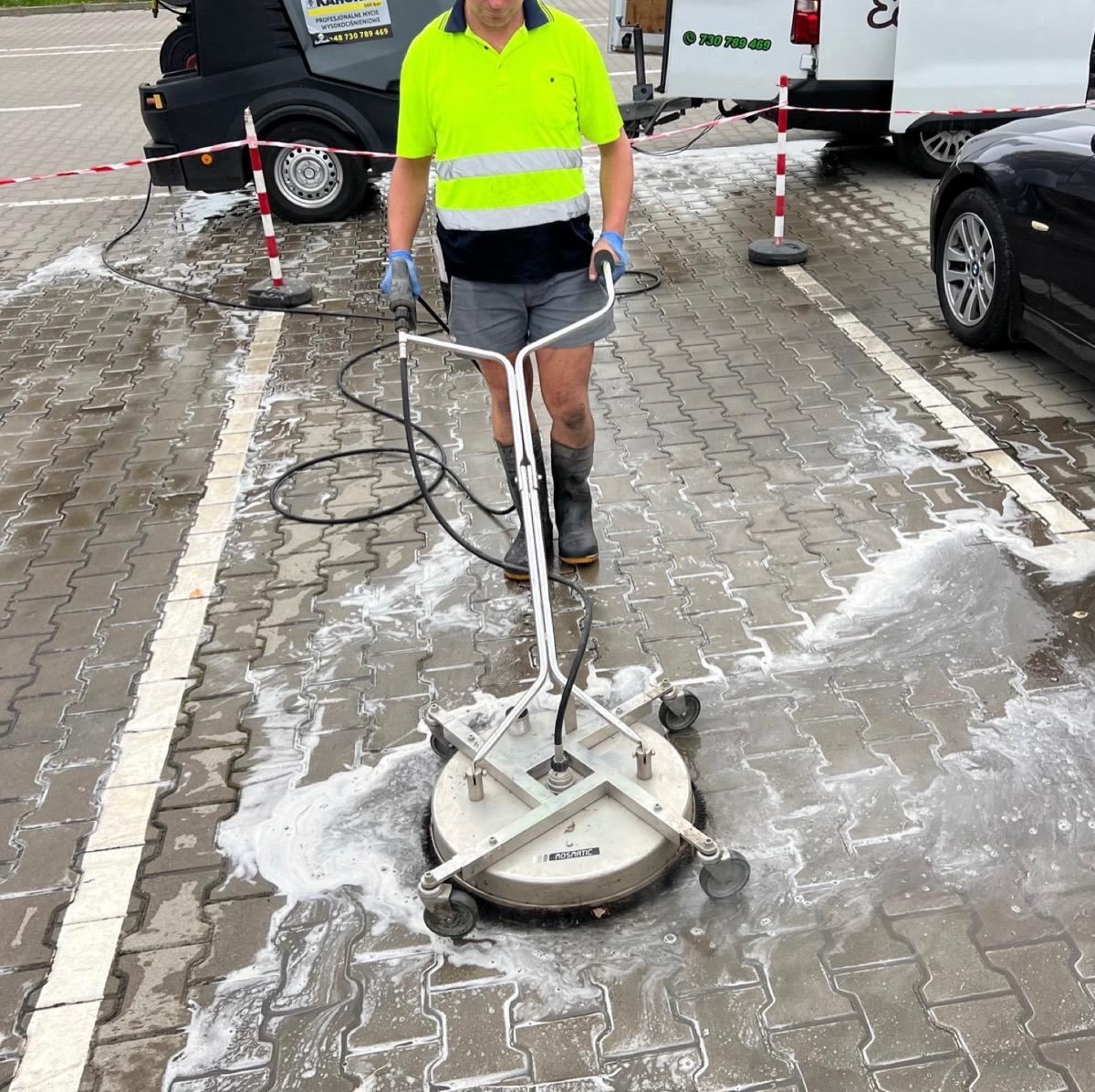 Usuwanie plam olejowych z kostki brukowej — pracownik ze szczotką T-racer